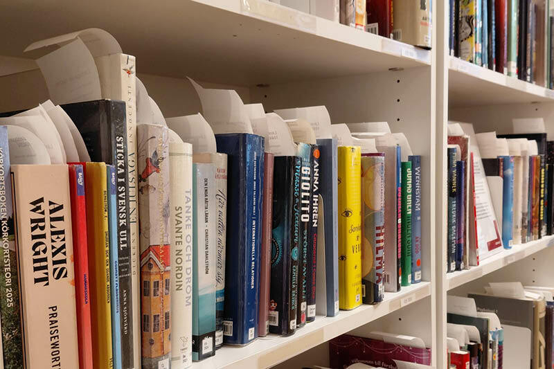 F&auml;rgglada bokryggar i en hylla. B&ouml;ckerna har kvitton som sticker upp mellan sidorna.